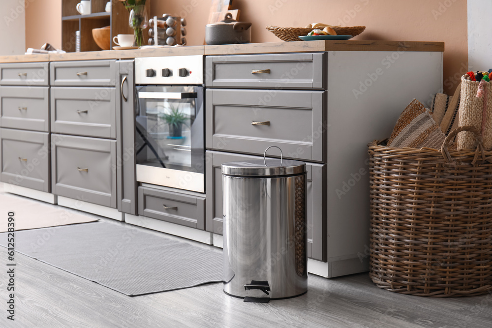 Metallic trash bin on floor in modern kitchen