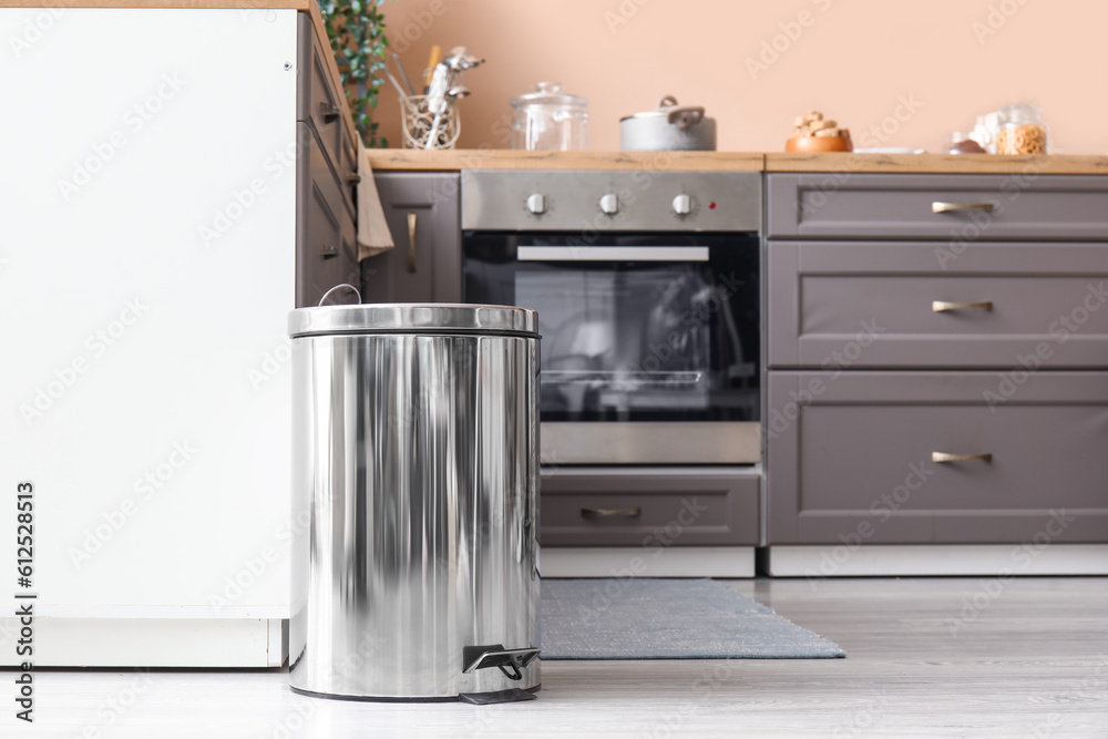 Metallic trash bin on floor in modern kitchen