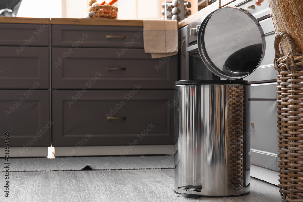 Opened metallic trash bin on floor in modern kitchen