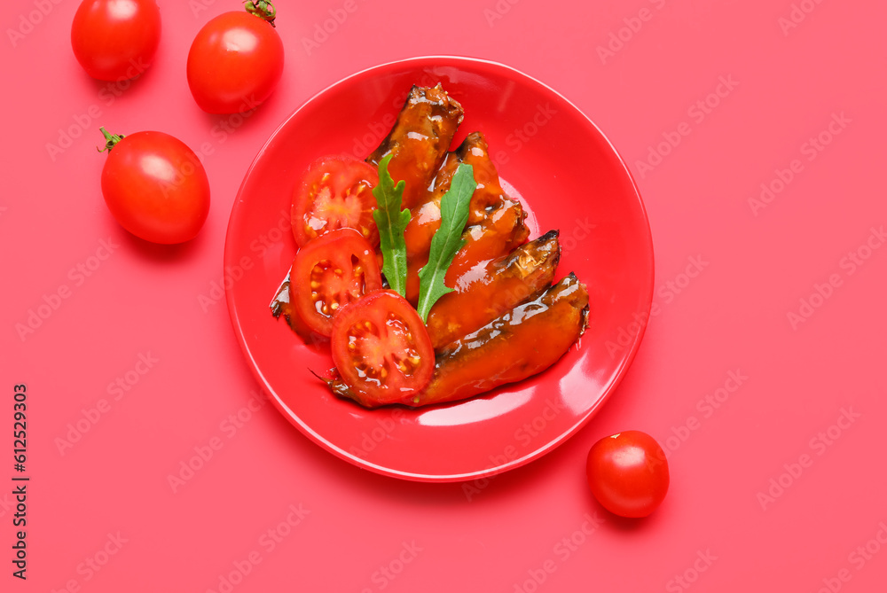 Plate with canned fish in sauce, arugula and tomatoes on red background