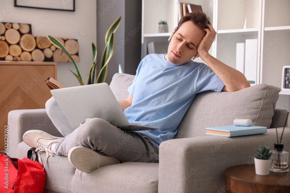 Male student with laptop preparing for exam at home