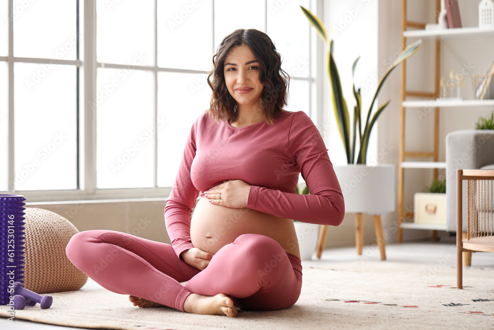 Sporty pregnant woman sitting at home