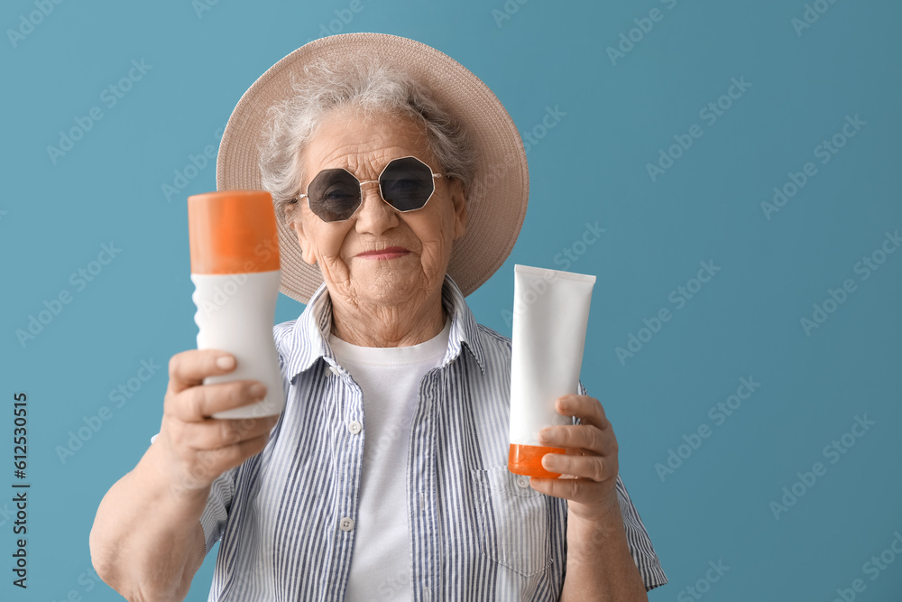 Senior woman with sunscreen cream on blue background