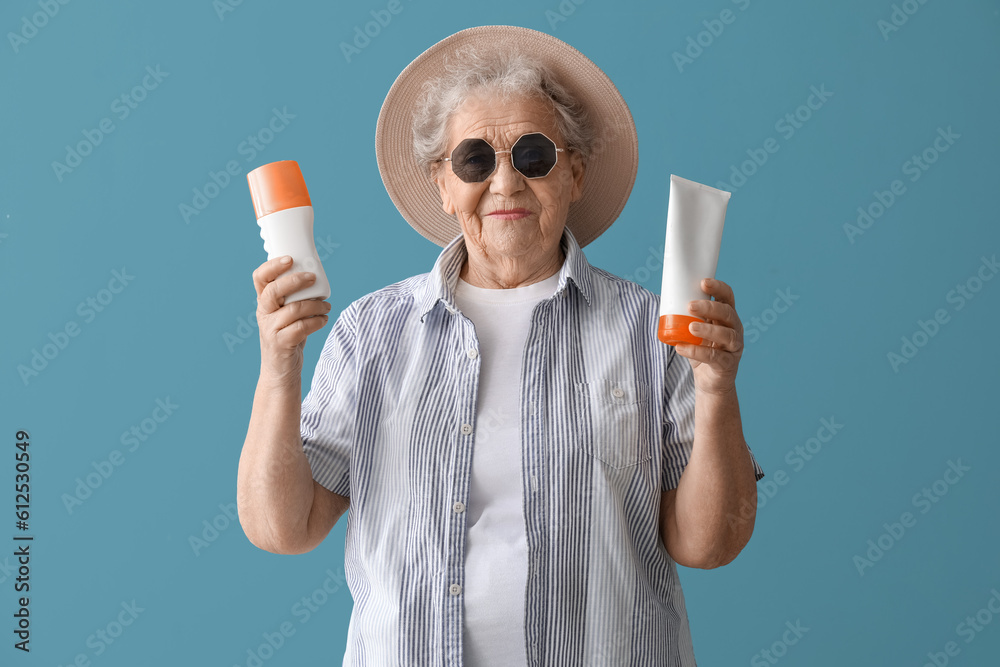 Senior woman with sunscreen cream on blue background