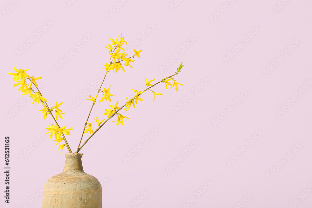 Vase with blooming tree branches on pink background