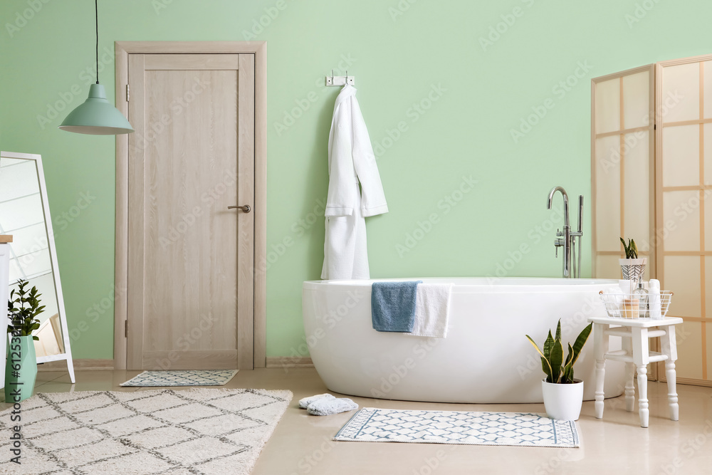 Interior of bathroom with bathtub, bathrobe and folding screen