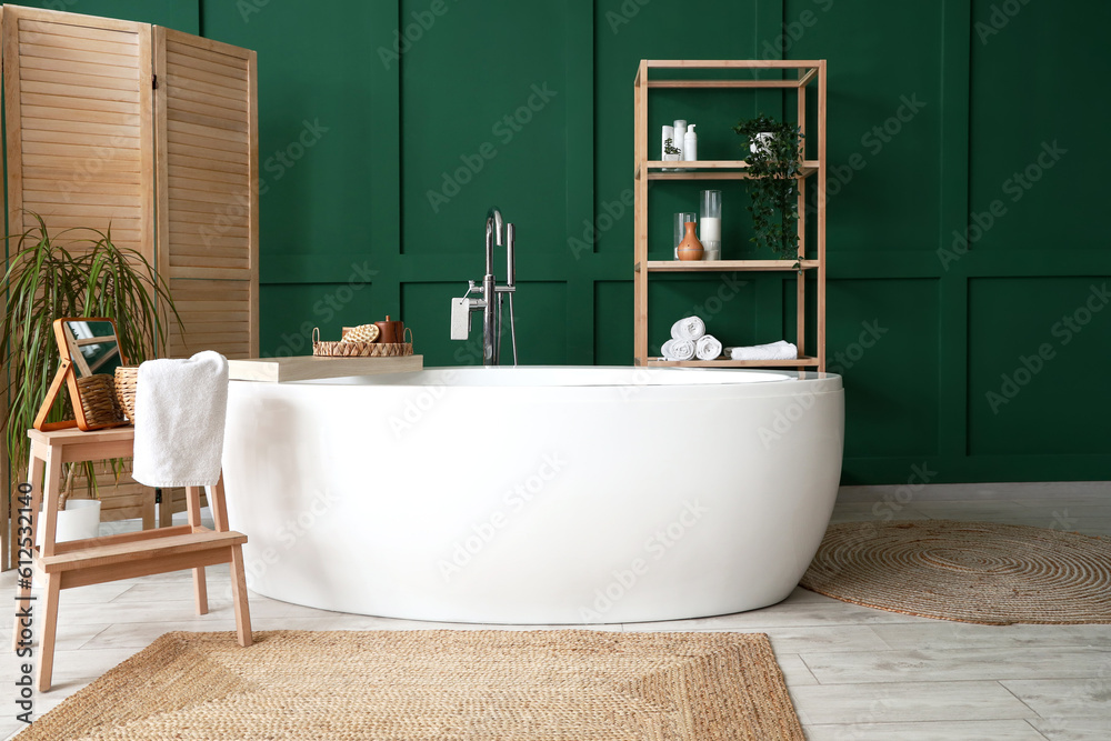 Interior of bathroom with bathtub, mirror on stepladder and folding screen