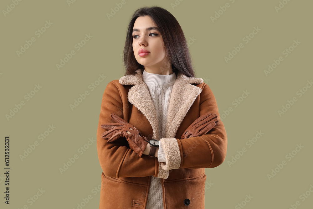 Stylish young woman in leather gloves on green background