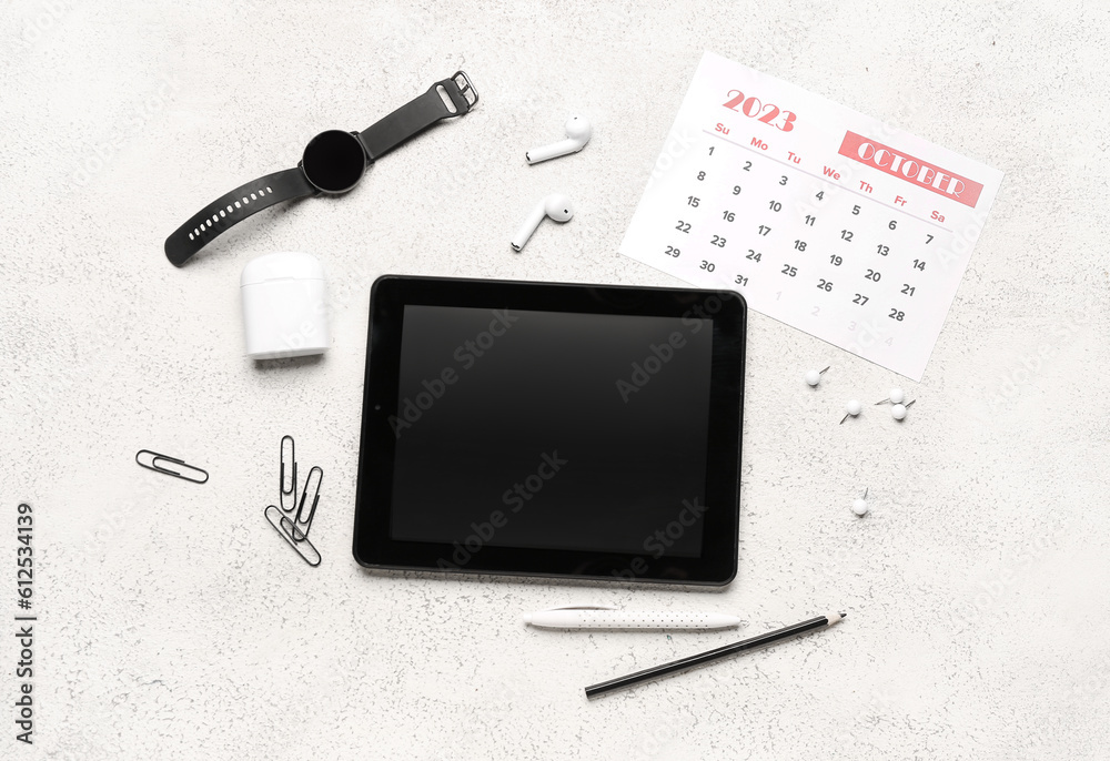 Composition with tablet computer, calendar, wristwatch and stationary on white table