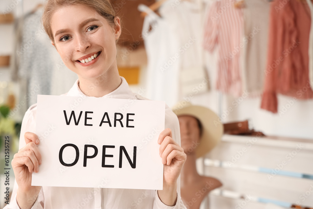 Female seller with opening sign in boutique, closeup