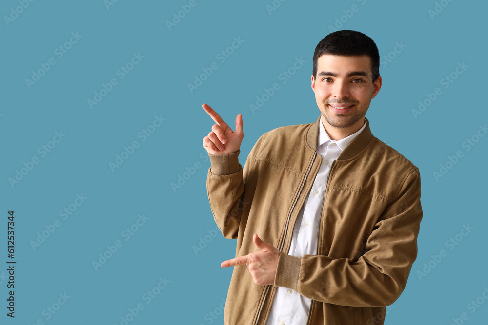 Young man pointing at something on blue background