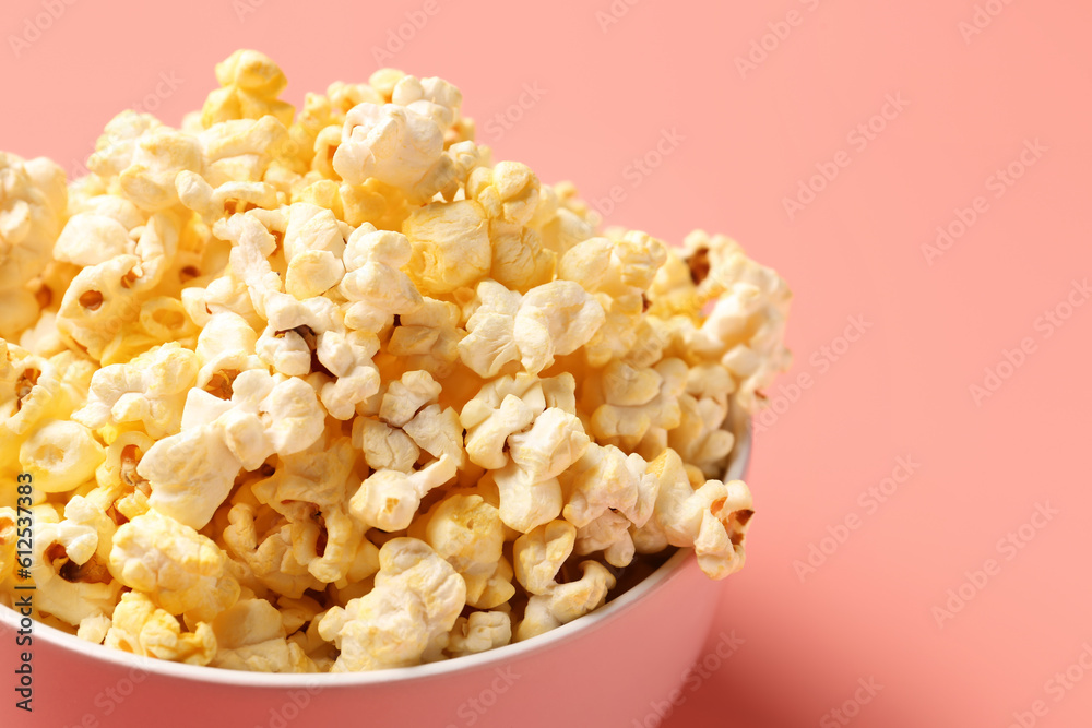 Bowl with crispy popcorn on pink background