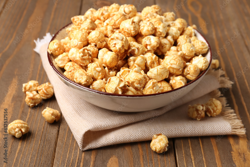 Bowl with crispy popcorn on wooden background