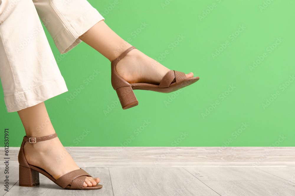 Female legs in stylish shoes near color wall