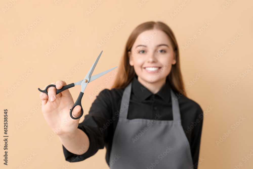 Female hairdresser with scissors on beige background, closeup