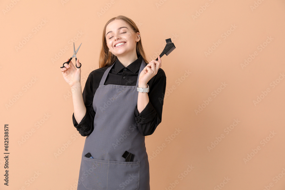 Female hairdresser with scissors and brush on beige background