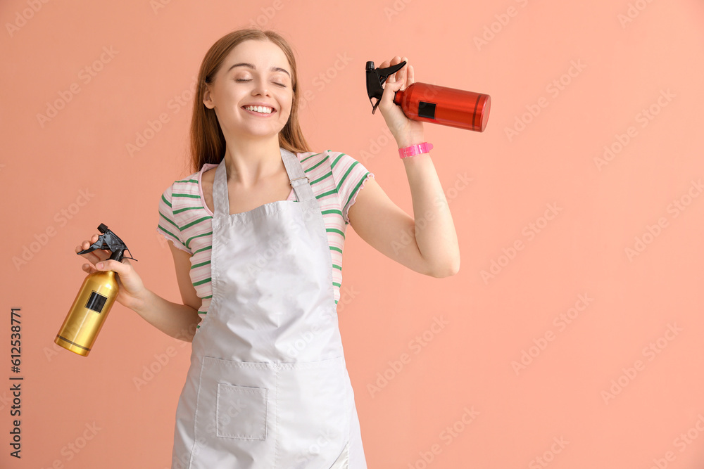 Female hairdresser with sprays on pink background