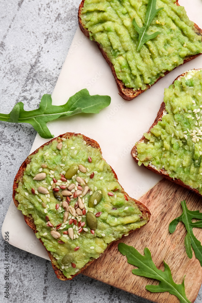 Board of tasty avocado toasts on light background