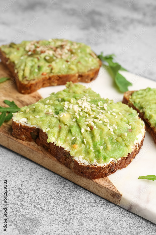 Board of tasty avocado toasts on light background