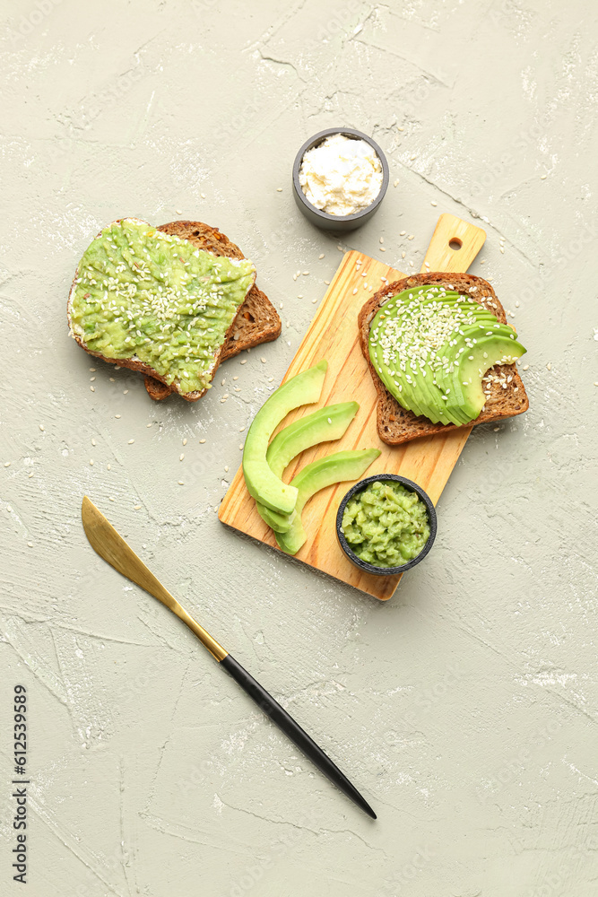 Wooden board of tasty avocado toasts on light background