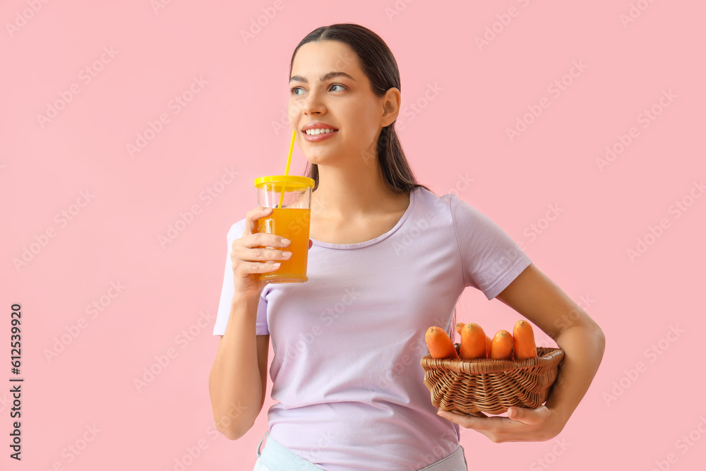 Young woman with glass of vegetable juice and carrots on pink background