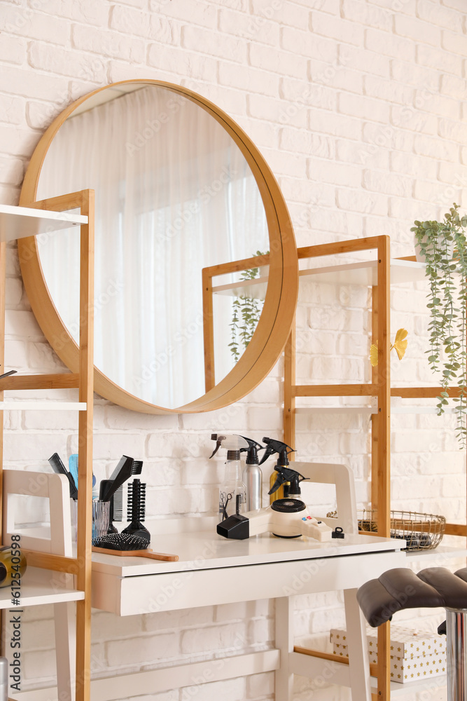 Different hairdressing tools on table near light brick wall in salon