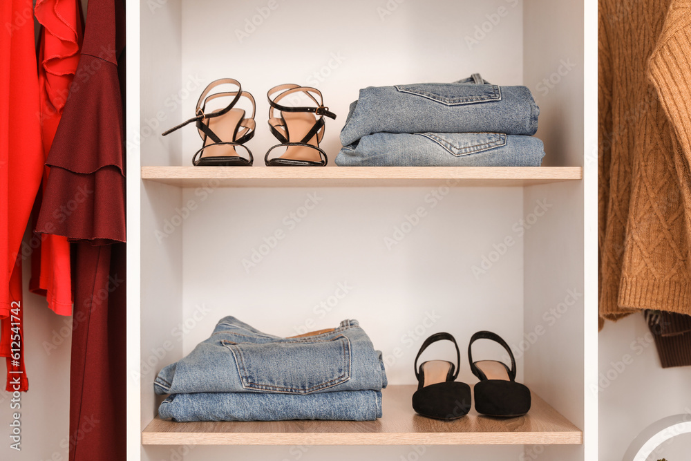 Shelves with stylish shoes and jeans in boutique