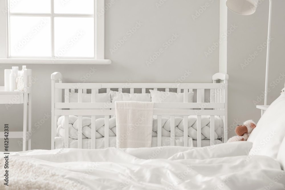 Baby crib in interior of light bedroom