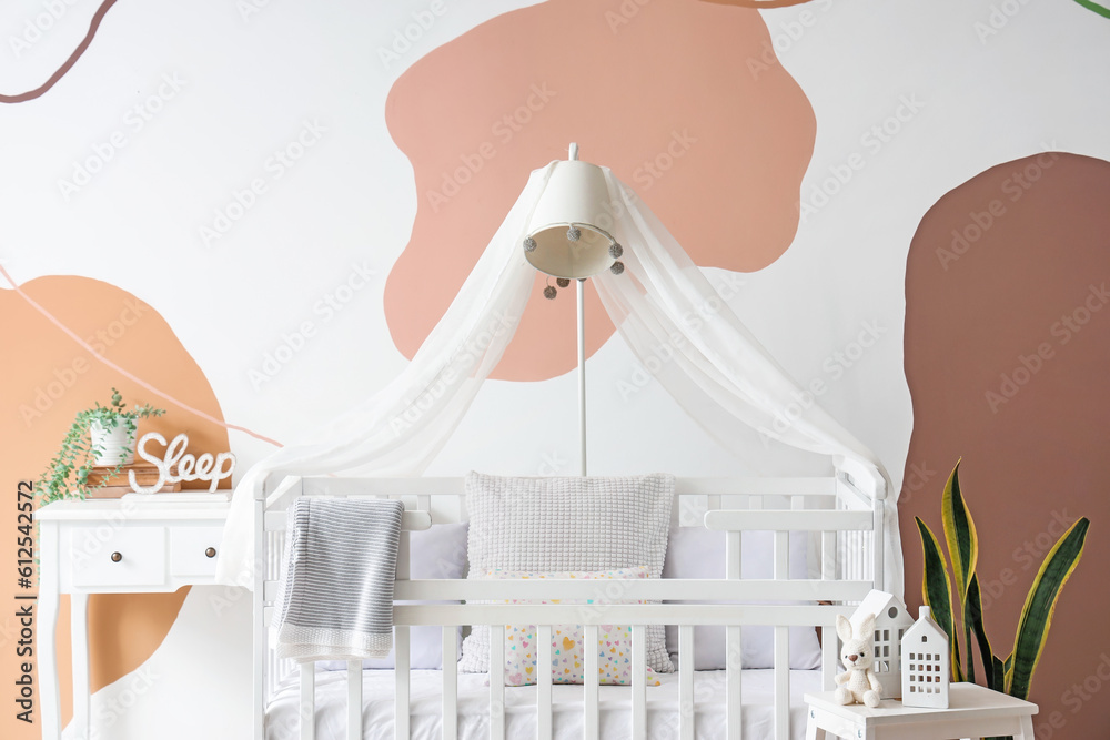 Interior of stylish bedroom with baby crib, lamp and table