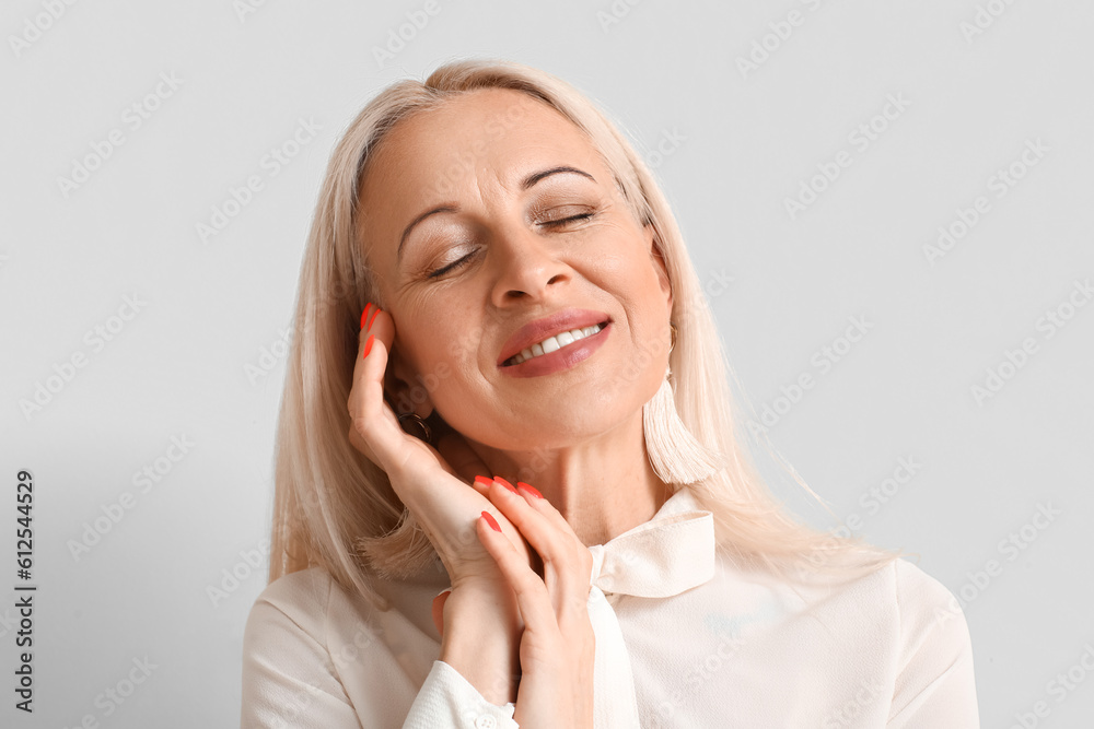 Mature blonde woman on light background, closeup