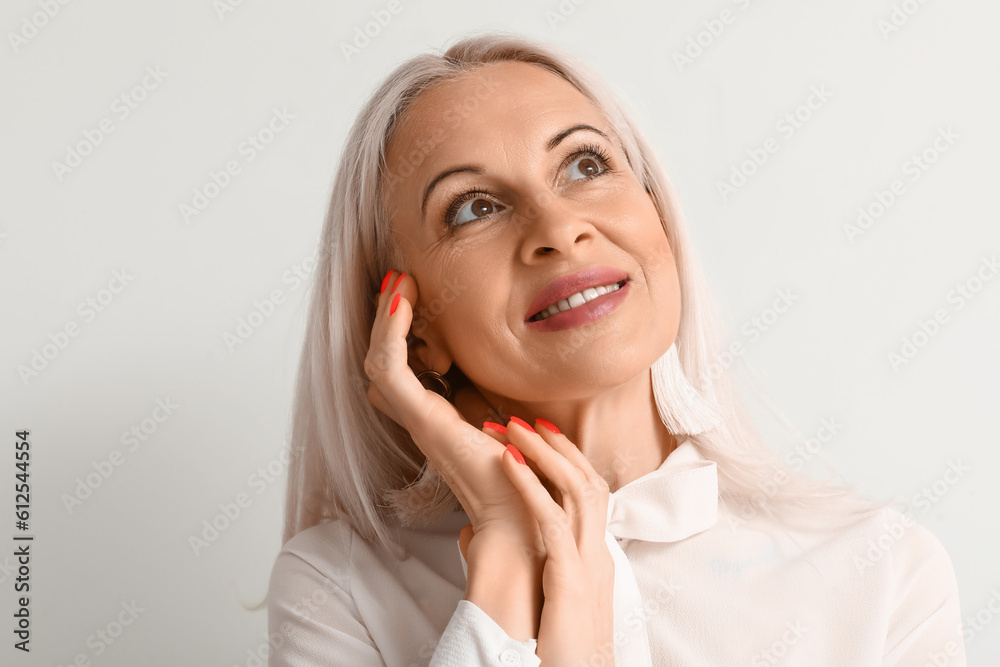 Mature blonde woman on light background, closeup