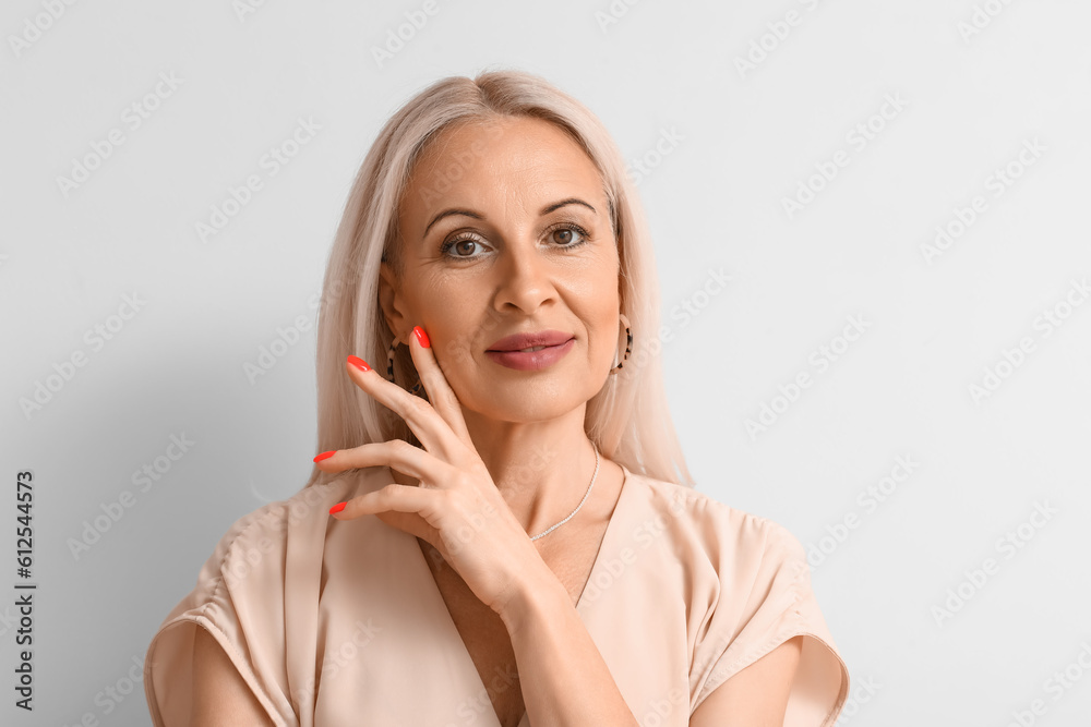 Mature blonde woman on light background, closeup