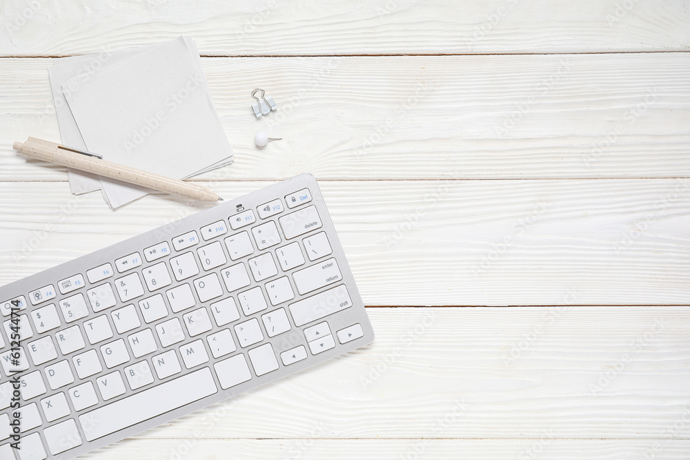 Sticky notes with keyboard on white wooden background