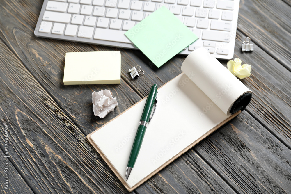 Sticky notes with keyboard and notebook on black wooden background