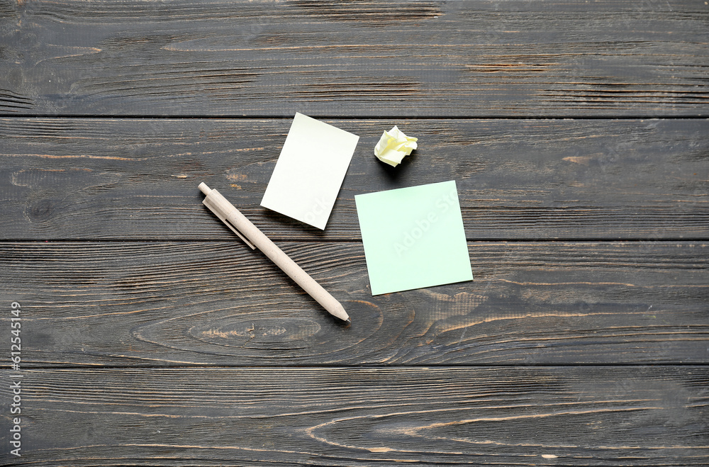 Sticky notes with pen on black wooden background