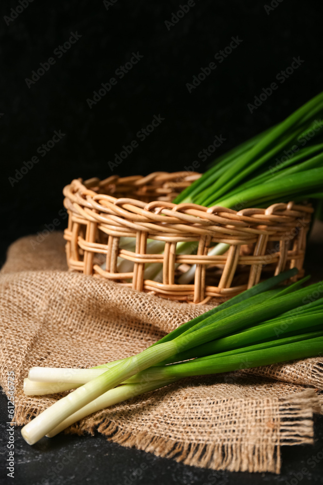 Wicker basket with fresh green onion on dark background