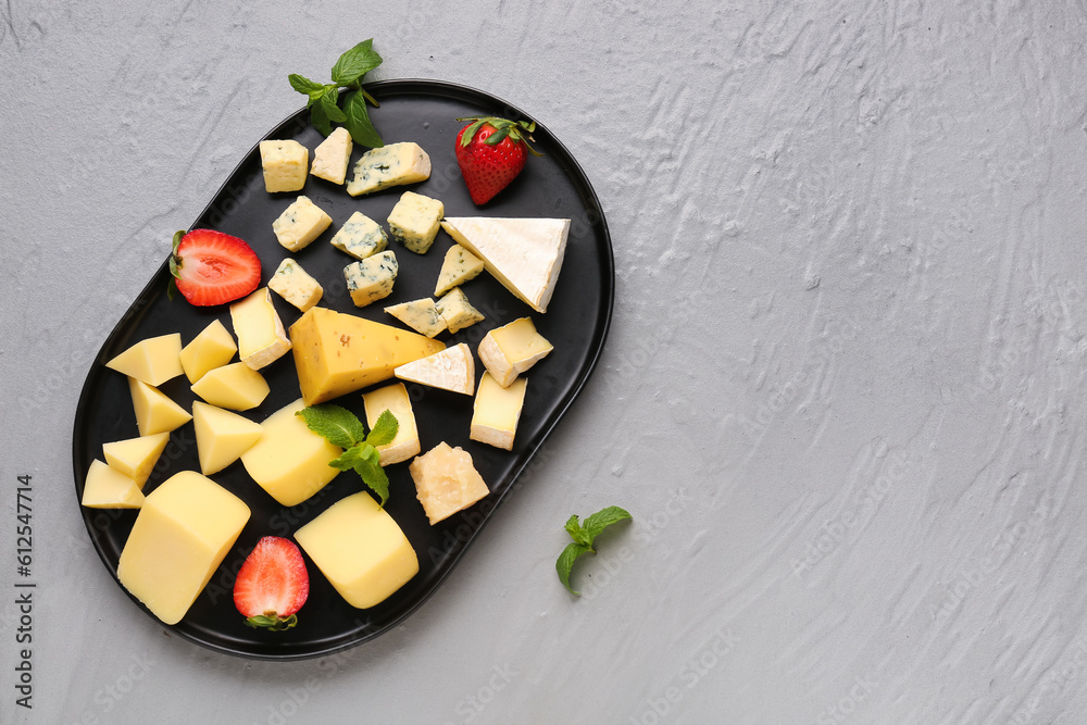 Tray with pieces of tasty cheese on grey background