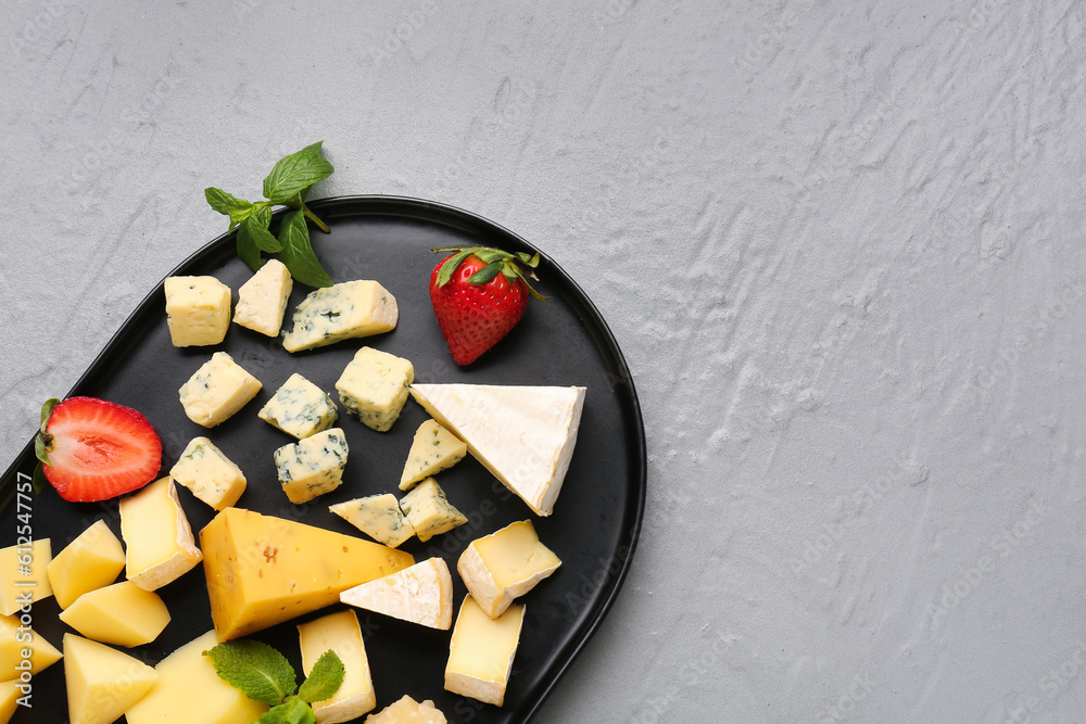 Tray with pieces of tasty cheese on grey background, closeup