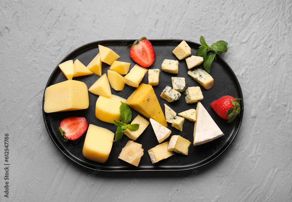 Tray with pieces of tasty cheese on grey background