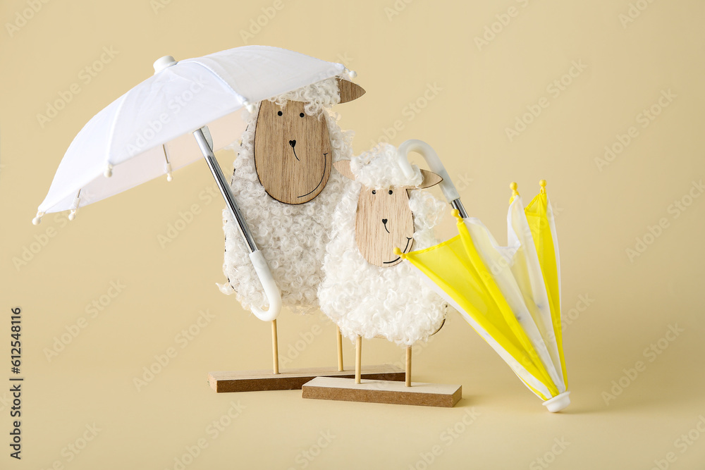 Creative composition with wooden toys sheep and mini umbrellas on beige background