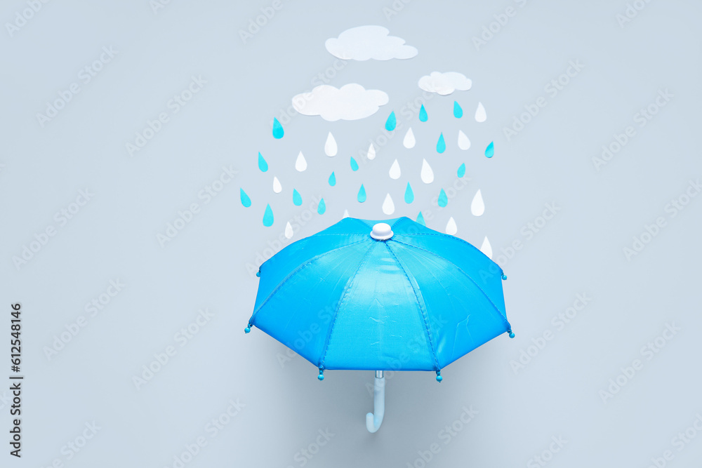 Creative composition with umbrella, paper clouds and raindrops on grey background