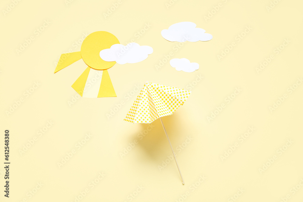 Creative composition with umbrella, paper clouds and sun on pale yellow background