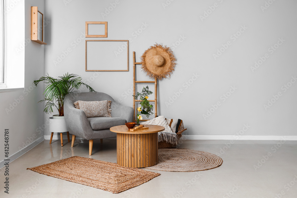 Interior of living room with ikebana on table and armchair