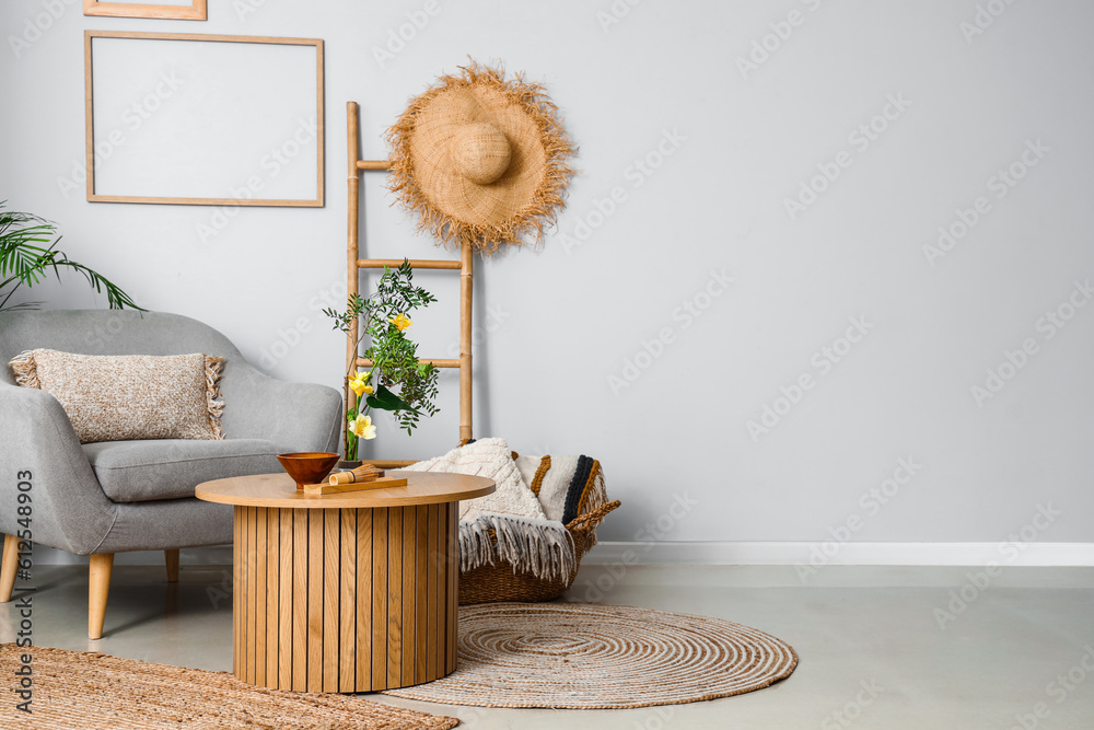 Interior of living room with ikebana on table and armchair