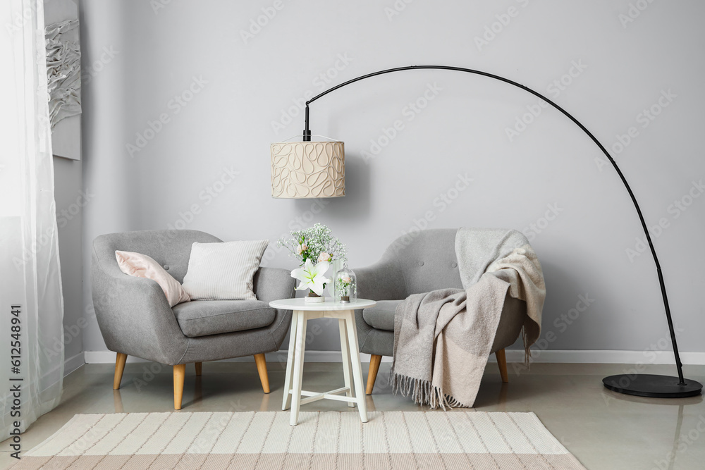 Interior of living room with ikebana on table and armchairs