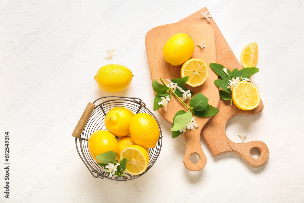 Boards and basket of lemons with blooming branches on white table