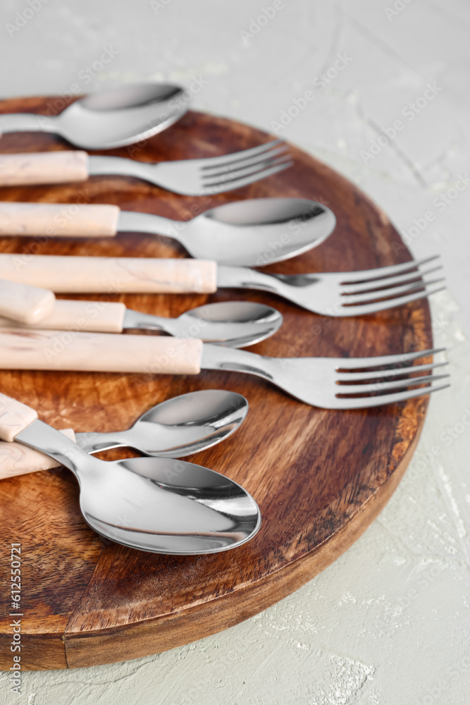 Board with stainless steel forks and spoons on grey background