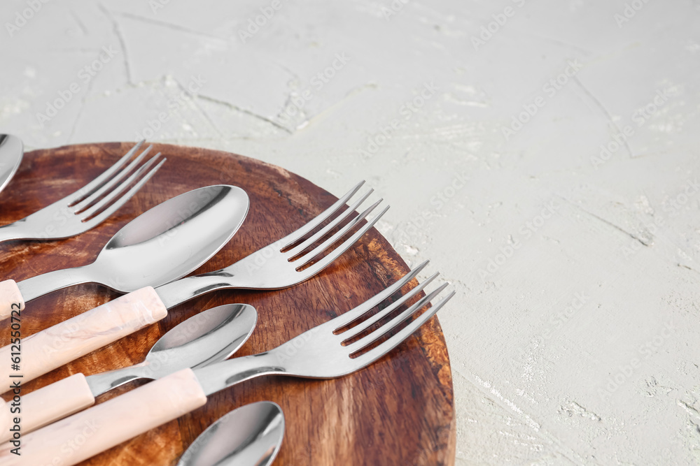 Board with stainless steel forks and spoons on grey background