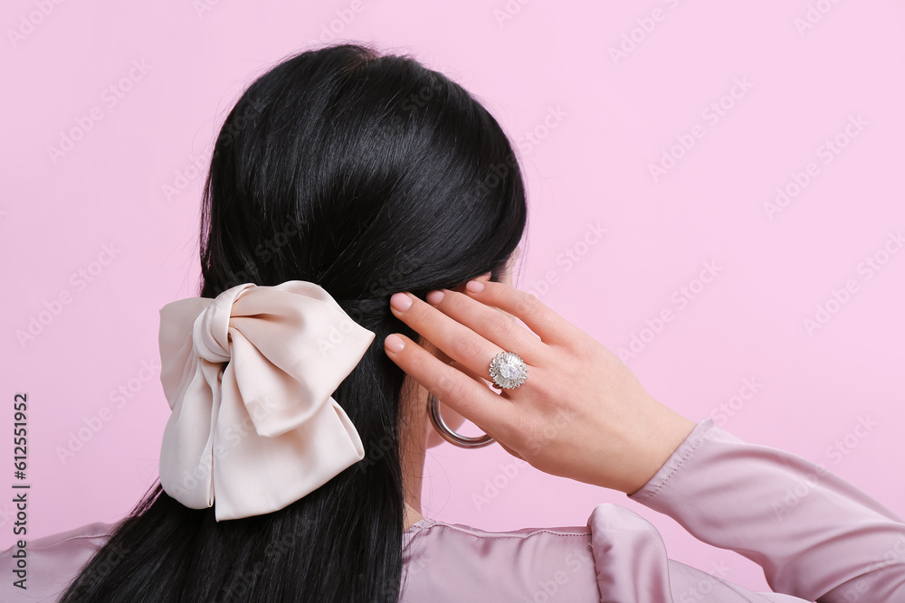 Beautiful young woman wearing elegant jewelry near pink wall