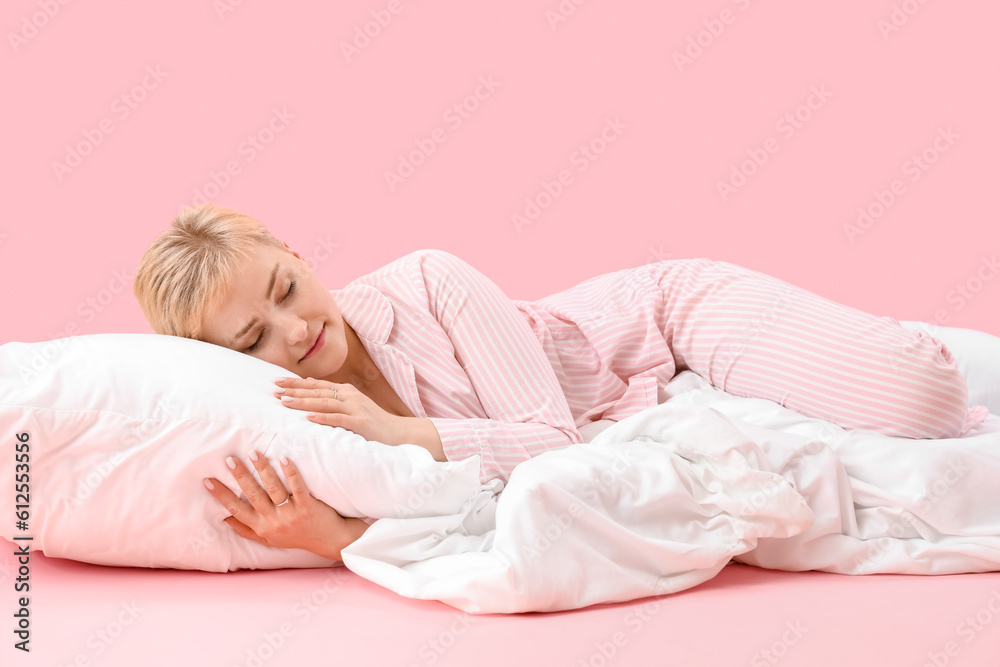 Young woman with pillow and soft blanket sleeping on pink background